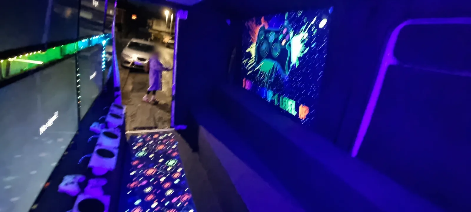 View through the neon gaming van with screens, seating and UV carpet